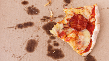 The remains of half-eaten pizza on a greasy box.