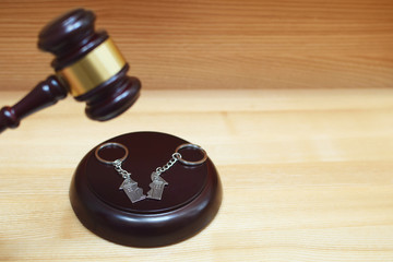 Judge gavel and key ring in shape of two splitted part of house on wooden background. Concept of...