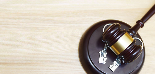 Judge gavel and key ring in shape of two splitted part of house on wooden background. Concept of...