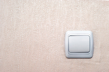 Old White Light Switch on Pinky Textured Wallpaper Background with Copy Space.