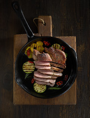Sliced grilled  barbecue steak in a pan on a wooden background