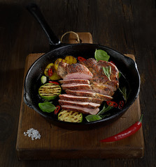 Sliced grilled  barbecue steak in a pan on a wooden background