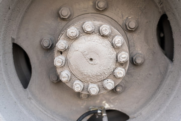 The hub of the rear wheel of a bus or a large machine with bolts and nuts, with a nipple for pumping the wheel is covered with road dirt, sand and salt mixture