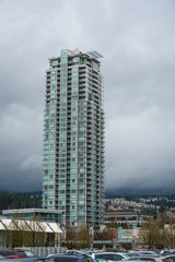 Fototapeta na wymiar High rise residential building in Vancouver on cloudy sky background. Appartment building with parking lot beside