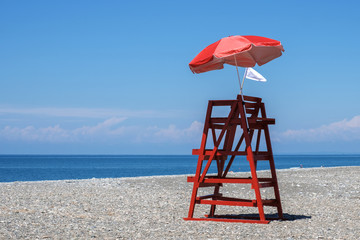 Red rescue tower and beach umbrella