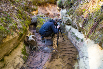 Red cliffs and photographer. Waterfall and rocks. Travel photo 2019.