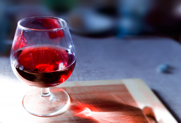Wine glass with red wine on a wooden board with a blurred background.