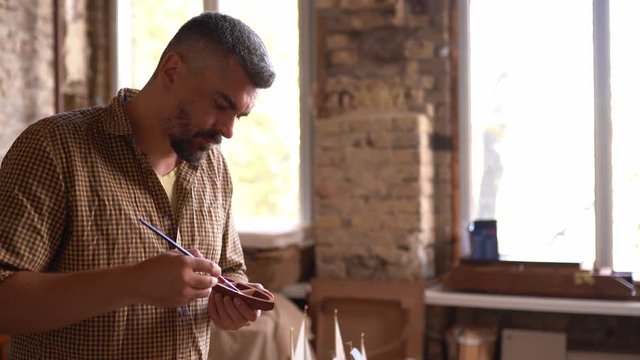 Craftsman painting ship figures in workshop