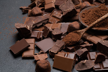 Dark or milk organic chocolate pieces, cocoa powder and truffle candies on dark concrete backgound