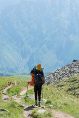 Fototapeta premium Kazbegi, Georgia - Jun 29 2018: Hiker on Mountain range on a hiking trail from Gergeti Trinity Church to Gergeti Glacier. a famous landscape in Kazbegi, Mtskheta-Mtianeti, Georgia.