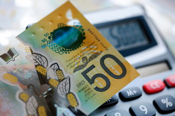 Australian fifty dollar bill over a calculator. The new 2019 issue is designed to deter...