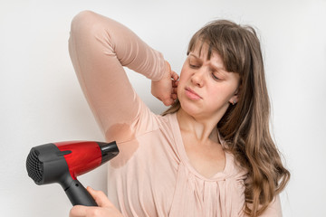 Woman is drying her sweating armpit with hair dryer