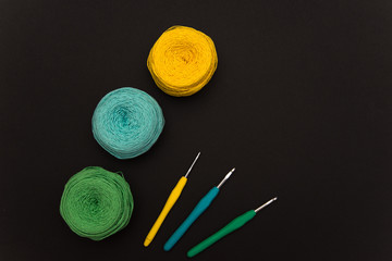 colored knitting yarn and hooks on a black background with space for text