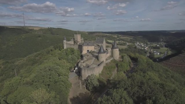 Descending from the front of the Bourscheid castle in Luxembourg. Showing the mountains and the forest. Sunny weather with clouds.