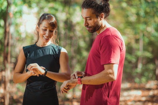Young couple Looking at Their Smart Watches After Outdoor Training
