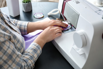 Obraz na płótnie Canvas Female tailor working on sewing machine in atelier