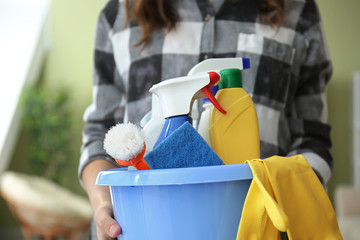 Woman with set of cleaning supplies in room