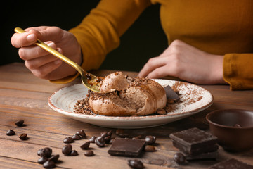 Woman eating tasty panna cotta at table