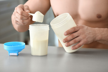 Obraz na płótnie Canvas Sporty man making protein shake at home