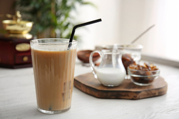Glass of tasty frappe coffee on white table