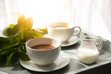 Cups of tasty frappe coffee and milk on tray