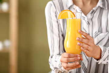 Woman with tasty orange juice in glass, closeup