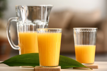 Glasses and jug of tasty orange juice on table