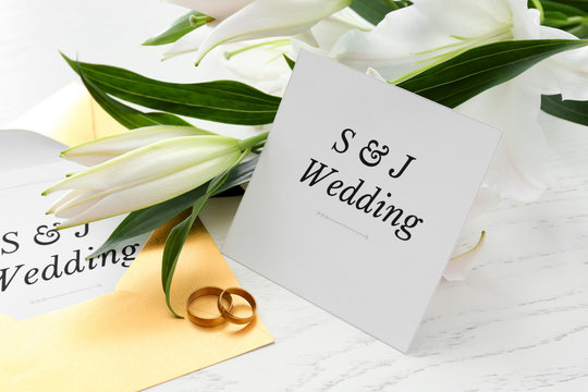 Wedding invitations, rings and flowers on table