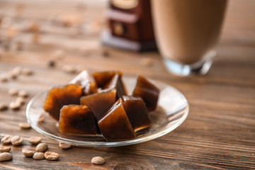 Plate with iced coffee cubes on wooden table