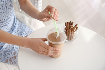 Woman drinking tasty frappe coffee at table