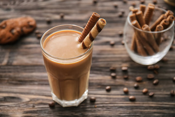 Glass of tasty frappe coffee on wooden table