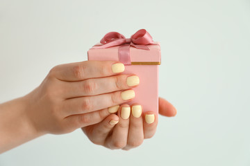 Female hands with gift box on light background