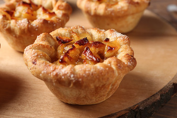 Tasty apple pies on wooden board, closeup