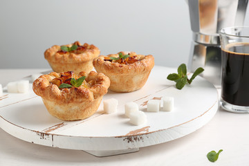 Board with tasty apple pies on white table