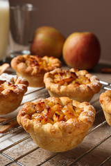 Cooling rack with tasty apple pies on table