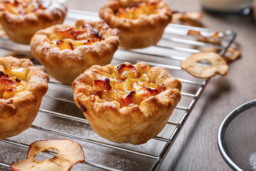 Cooling rack with tasty apple pies on table