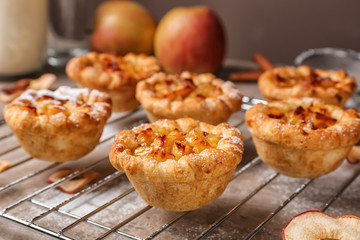 Cooling rack with tasty apple pies on table