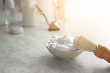 Bowl with shaving foam and brush on table
