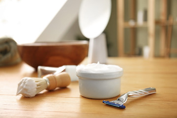 Fototapeta na wymiar Bowl with shaving foam, razor and brush on table in bathroom