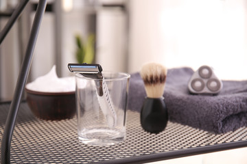 Glass with razor and accessories on table