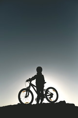 Fototapeta na wymiar Silhouette of a little girl with a bicycle at sunset
