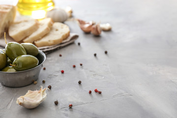 Ladle with tasty olives and spices on grey table