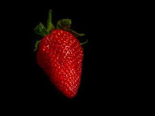 Erdbeere vor schwarzem Hintergrund mit Wassertropfen