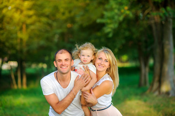 Family еnjoying time together. Happy young family spending time together having fun in summer park, people concept. Loving family