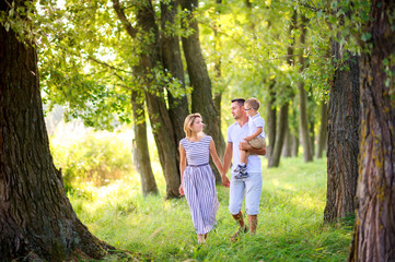 Fototapeta premium Loving family. Happy young family spending time together having fun in summer park, people concept. Family еnjoying time together
