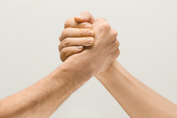 Friends greetings sign or disagreement. Two male hands competion in arm wrestling isolated on grey...
