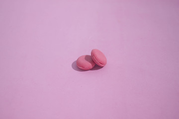 Obraz premium Macaroons on a colored background, picture of colorful french macarons cookies. Macaron French pastry on a pink background, minimal concept.