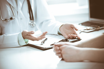 Doctor and  female patient sitting at the desk and talking  in clinic near window. Medicine and health care concept. Green is main color