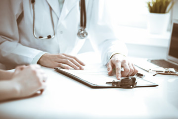 Doctor and  female patient sitting at the desk and talking  in clinic near window. Medicine and health care concept. Green is main color