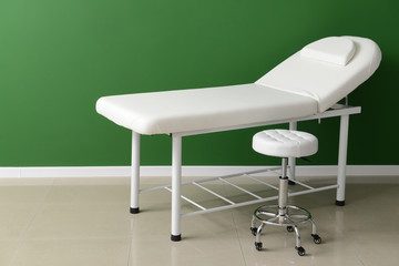 Treatment couch with stool near color wall